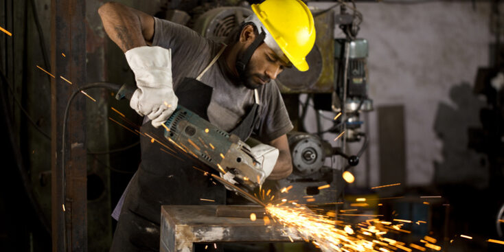 Mechanic using circular saw grinder tool at factory