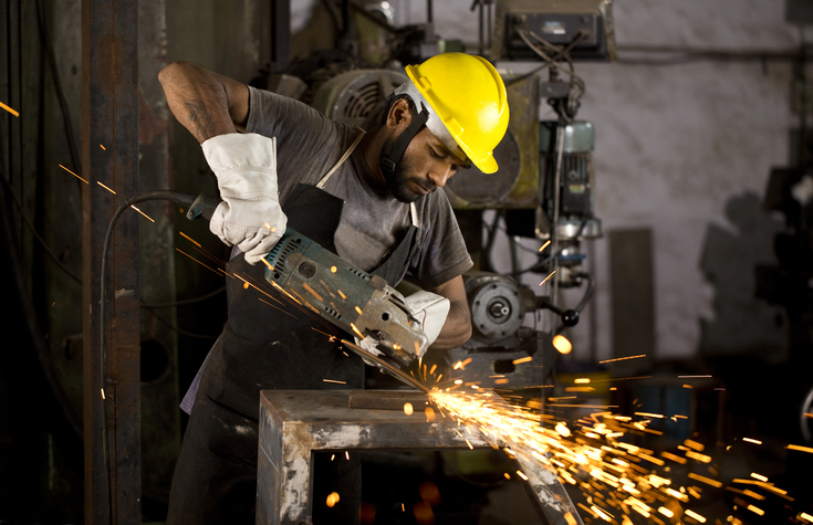 Mechanic using circular saw grinder tool at factory
